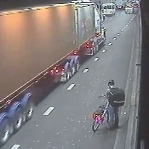 A food delivery cyclist is seen on CCTV in Sydney’s Eastern Distributor tunnel as a truck passes. 