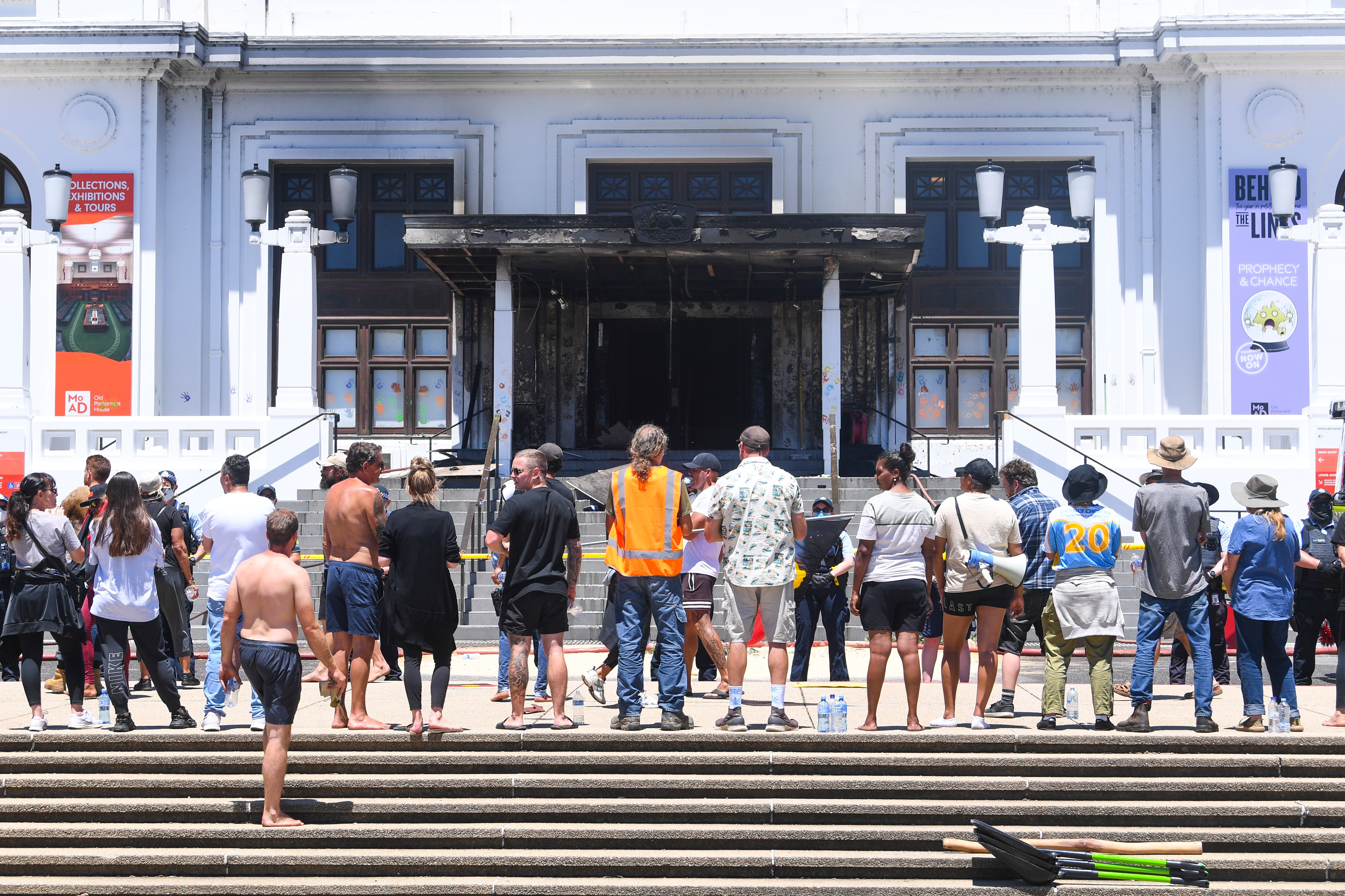 Protesters stand in front of the burnt-out front doors of the Old Parliament House.