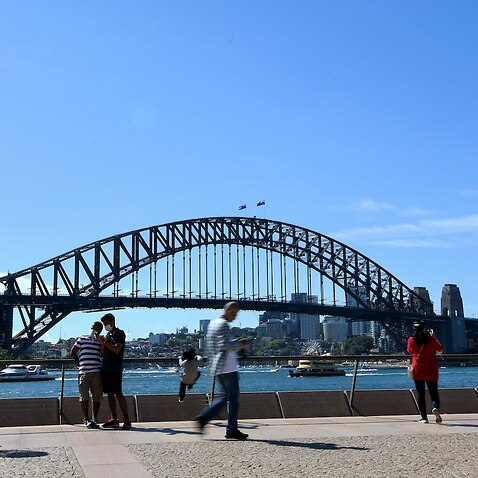People walk past the Sydney Harbour Bridge 