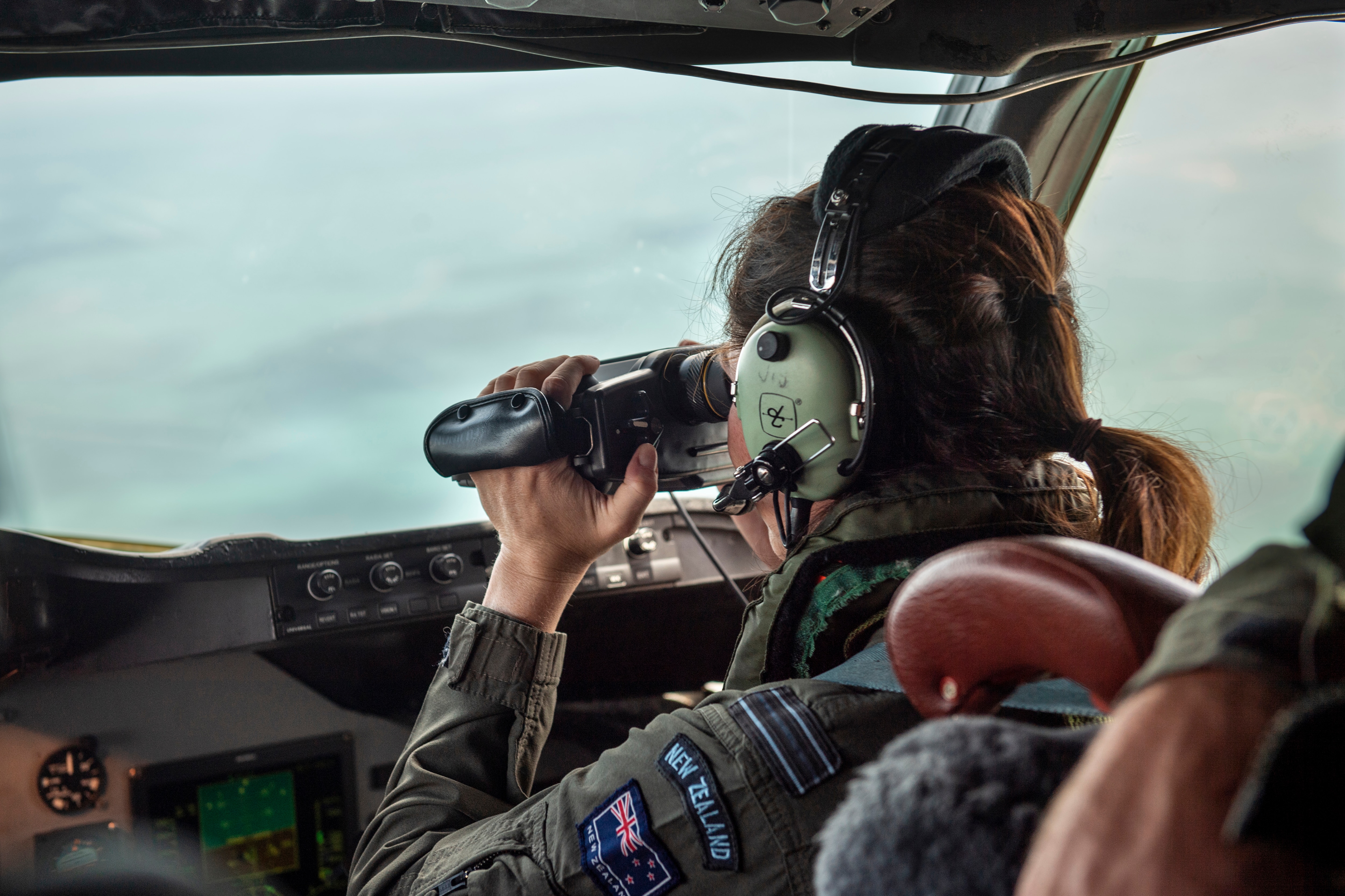 A crew member from a New Zealand Air Force Orion aircraft observes an area of Tonga that suffered heavy ash fall.