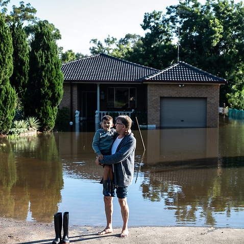 David Williams and his son Lucas (6) stand in front of a home affected by the flood on 23 March in Londonderry, Sydney.