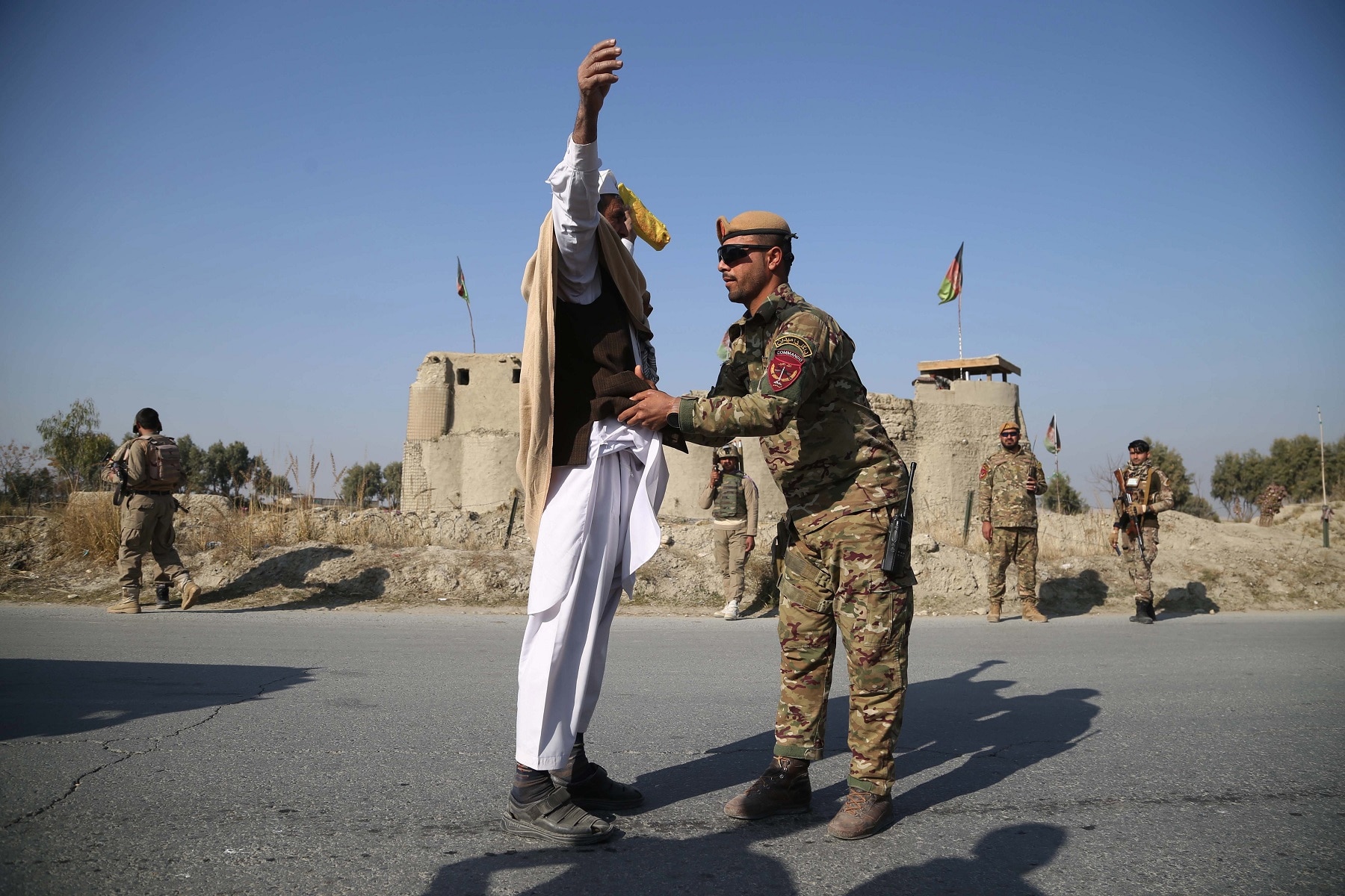 Afghan security officials check people at a checkpoint on the outskirts of Jalalabad, Afghanistan.