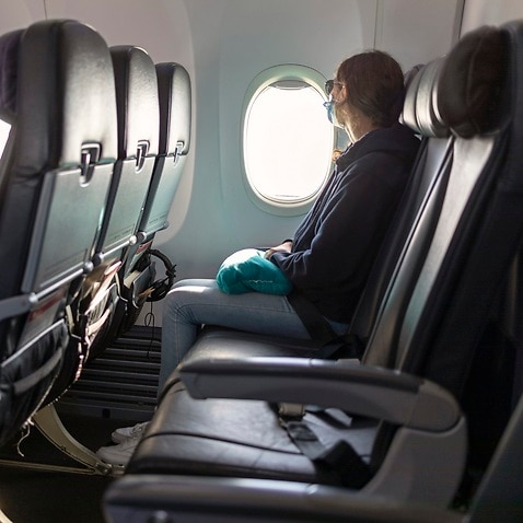 Air travel, passenger looking out airplane window, empty seats, COVID-19