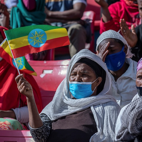 A woman holds a national flag as she waits to give blood in support of the country's military, at a stadium in the capital Addis Ababa, Ethiopia.
