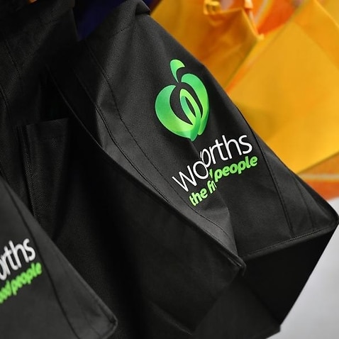 close up of black shopping bags showing Woolworths name and logo