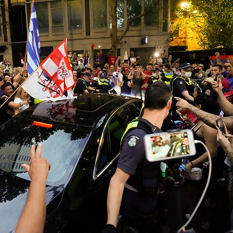 Fans of Serbian Novak Djokovic and police surround a car as it leaves the offices of lawyers following his court win ahead of the Australian Open in Melbourne, Australia, Monday, Jan. 10, 2022. An Australian judge has reinstated Djokovic's visa, which was