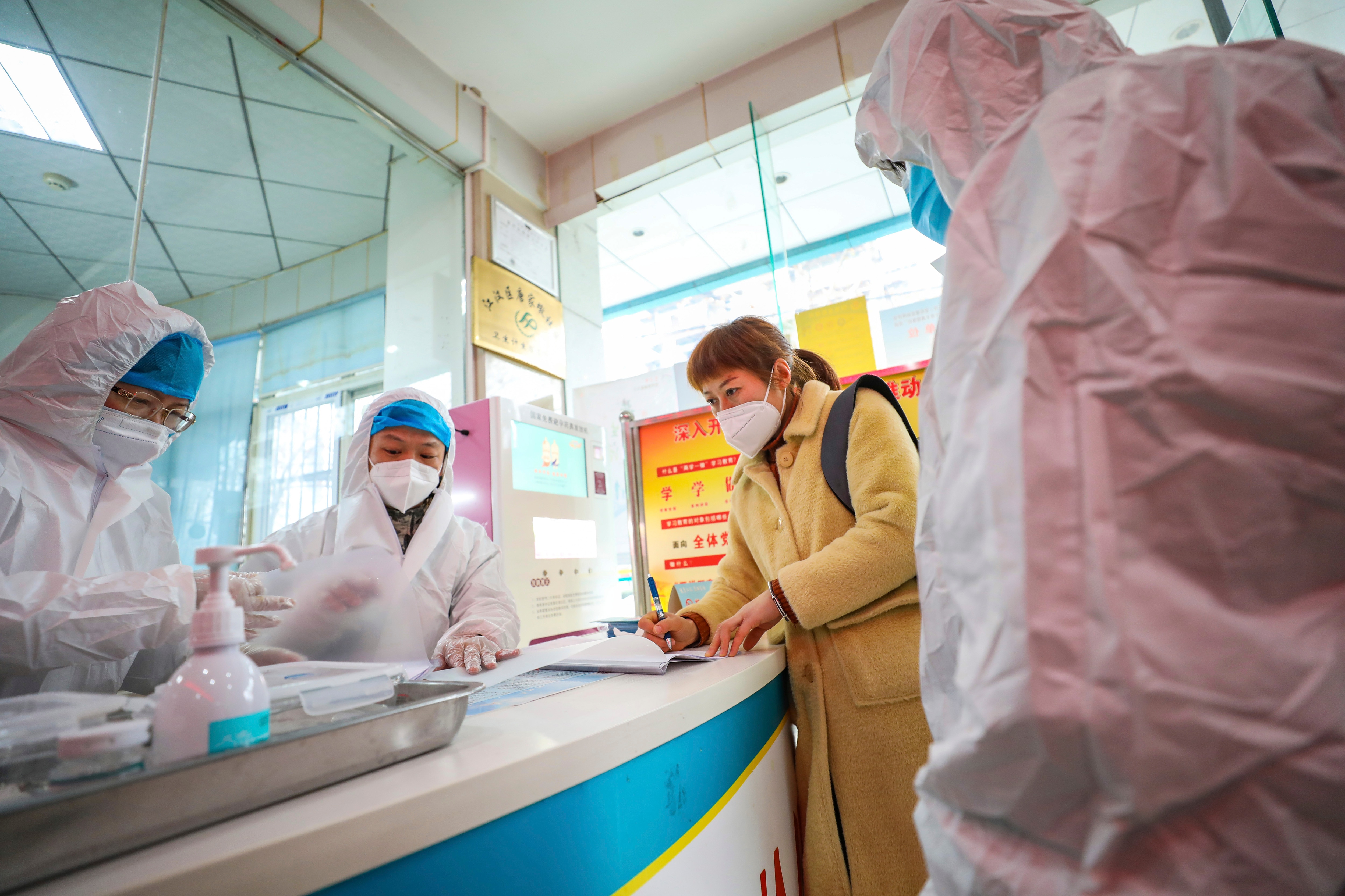 Medical workers in protective gear talk with a woman suspected of being ill with coronavirus at a community health station in Wuhan.