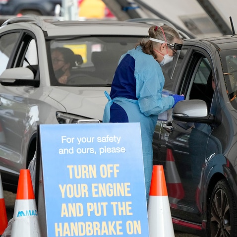 Staff collect samples at a drive-through COVID-19 testing clinic at Bondi Beach in Sydney, Australia, Saturday, Jan. 8, 2022. Australia's most populous state has reinstated some restrictions and suspended elective surgeries as COVID-19 cases surged to ano