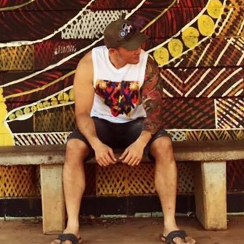 Image of Add sitting on a stone bench in front of an aboriginal mural on the wall