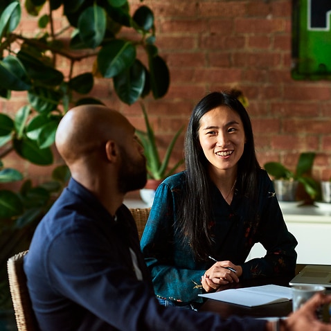 Mid adult Asian woman smiling towards male colleague