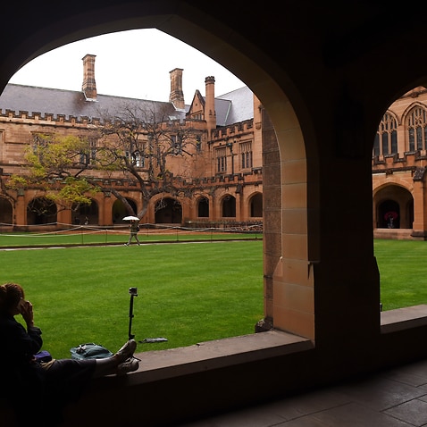 A student sits next to the quadrangle at the University of Sydney.