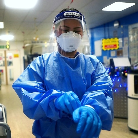 A nurse puts on full PPE on a ward for COVID-19 patients at King's College Hospital in south east London.