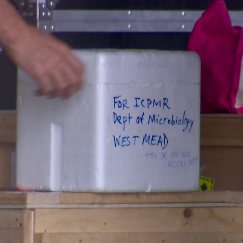 A member of the Australian Defence Force carries a white styrofoam box marked 'Dept of Microbiology Westmead' shortly before it departed Christmas Island.