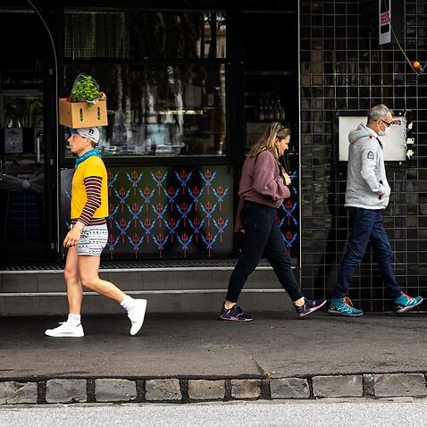 A man walks around balancing a box on his head in St Kilda, Melbourne