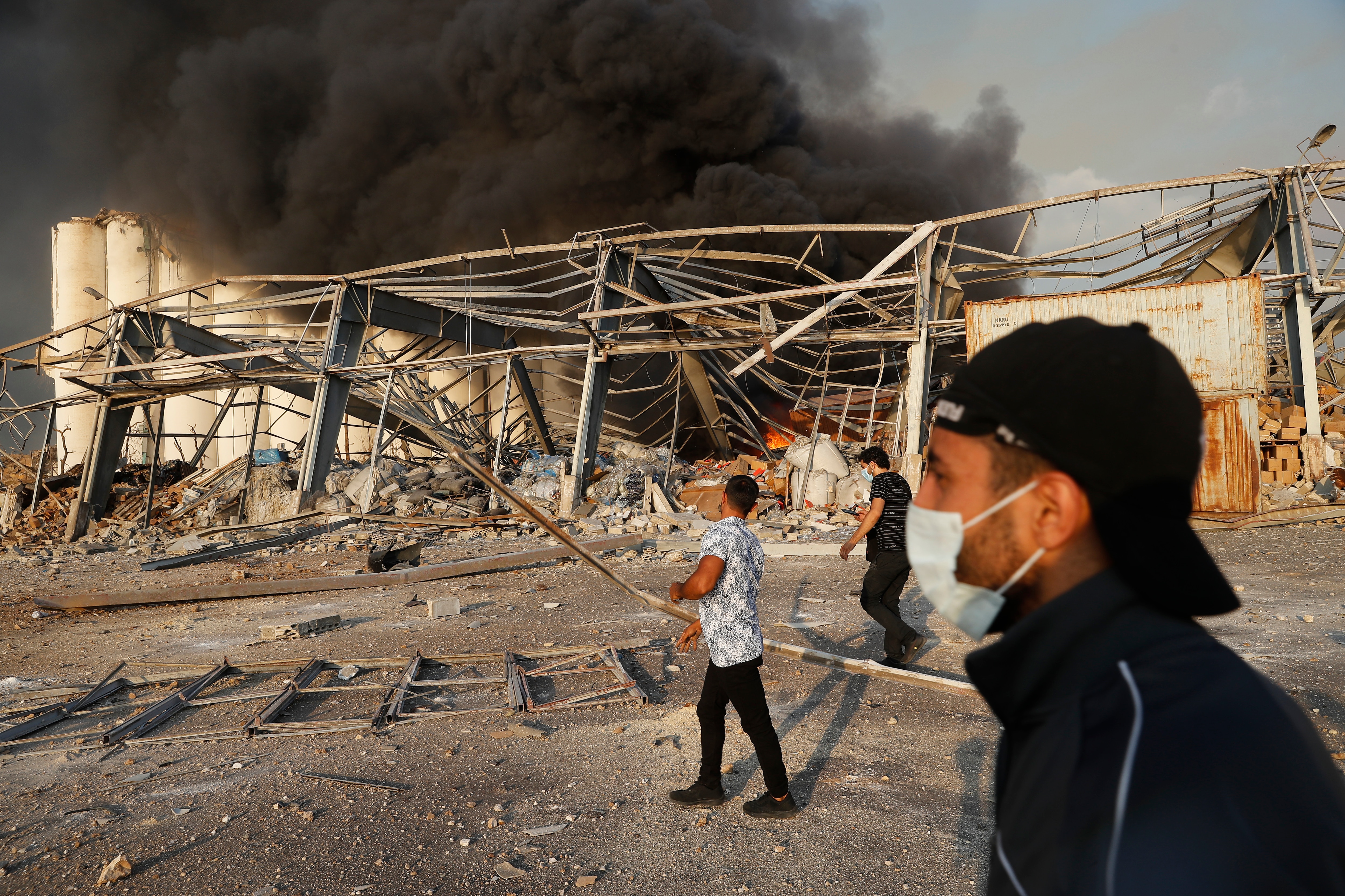 Lebanese port workers walk at the explosion scene that hit the seaport of Beirut, Lebanon, Tuesday, 4 August, 2020. 