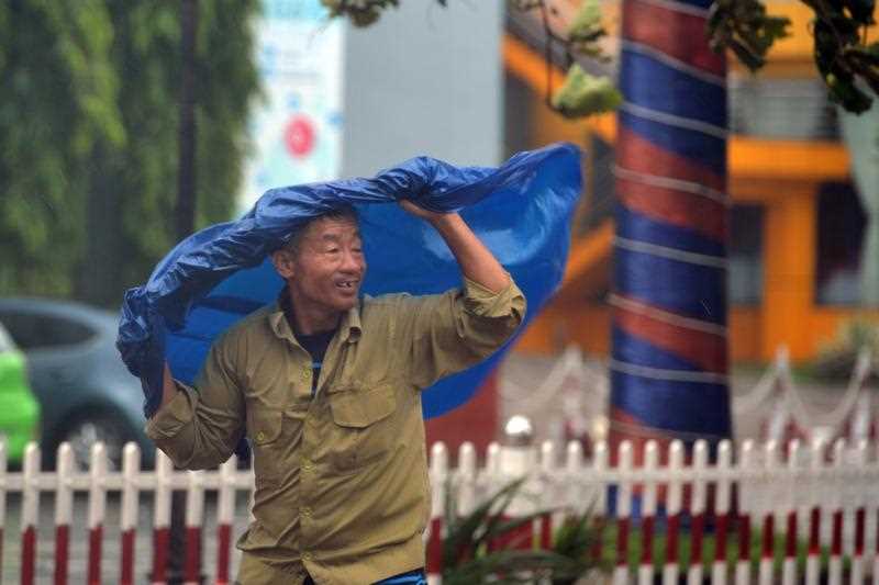 A man holding a raincoat walks at a street, in Ha Binh province, Vietnam, 15 September 2017.