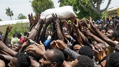 Residents reach out for a bag of donated rice near a truck loaded with relief supplies in Vye Terre, Haiti.