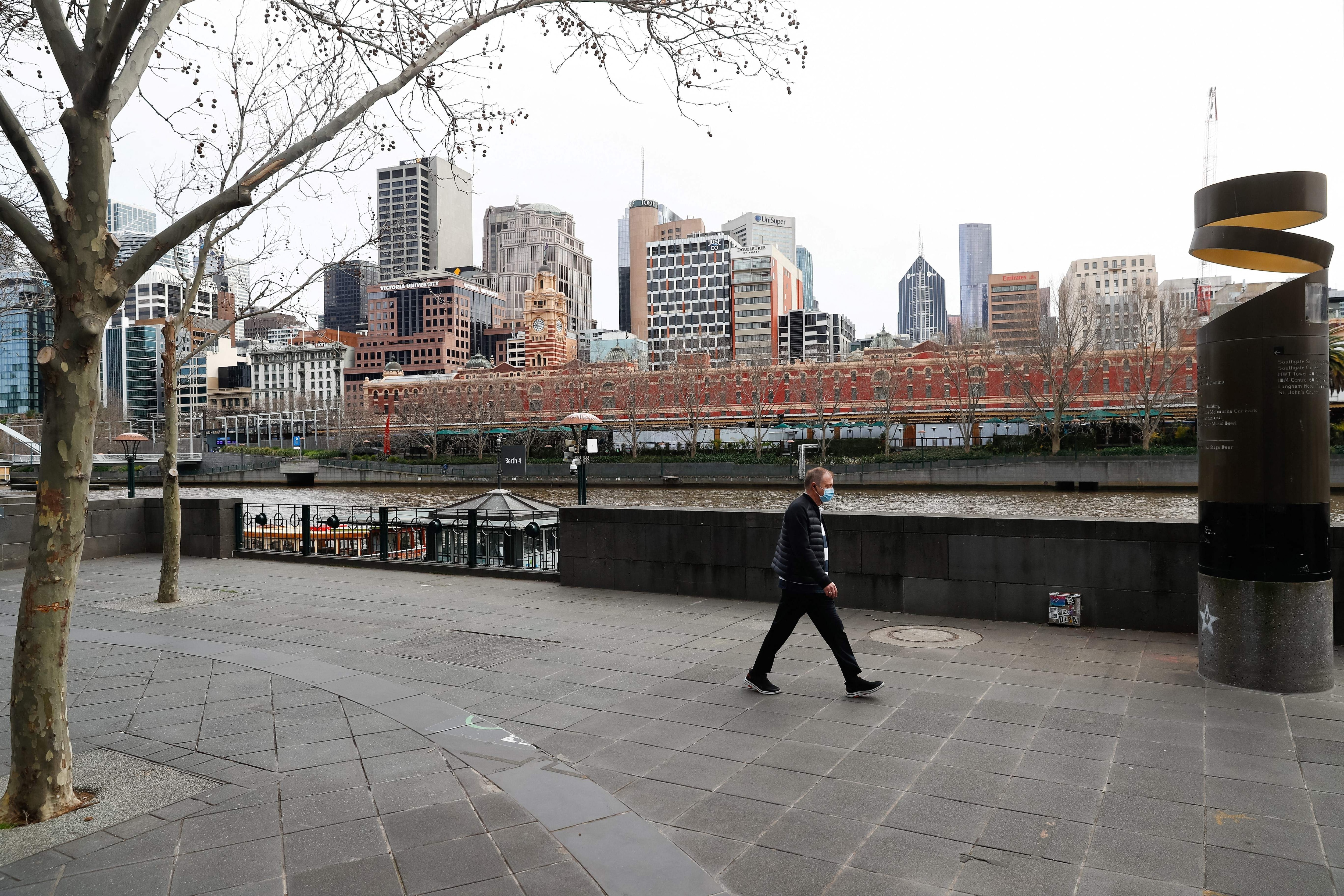 A man walks along Southbank in downtown Melbourne on August 6, 2021, amid a sixth lockdown for the city in efforts to bring the Delta outbreak to heel.