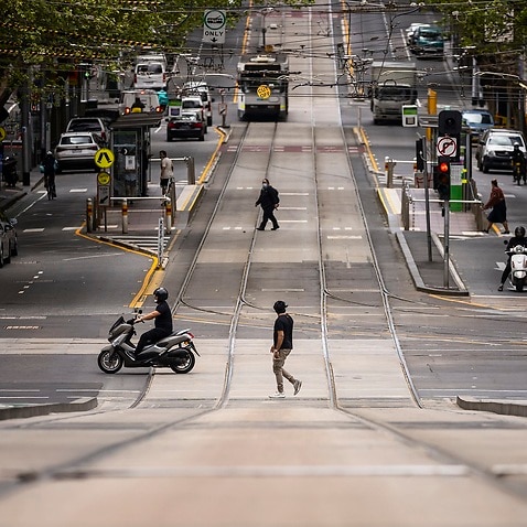 People are seen crossing Collins Street in Melbourne, the world's most locked-down city