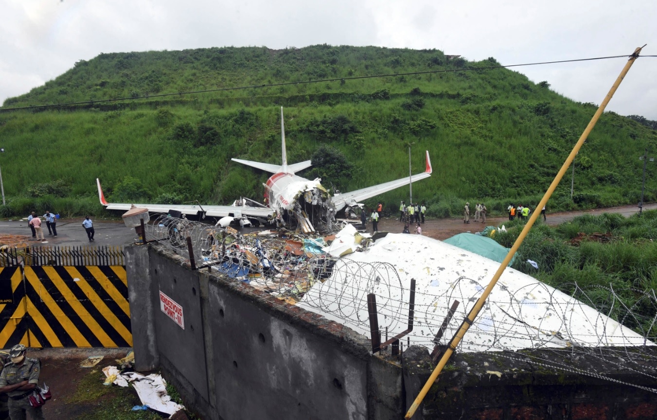 Officials stand by the debris of the Air India Express flight that skidded off a runway while landing in Kozhikode, Kerala state, India, Saturday, Aug. 8, 2020. Officials stand by the debris of the Air India Express flight that skidded off a runway while landing in Kozhikode, Kerala state, India, Saturday, Aug. 8, 2020.