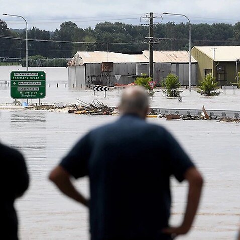 People watch on as debris carried by floodwater in the swollen Hawkesbury river in Sydney. 