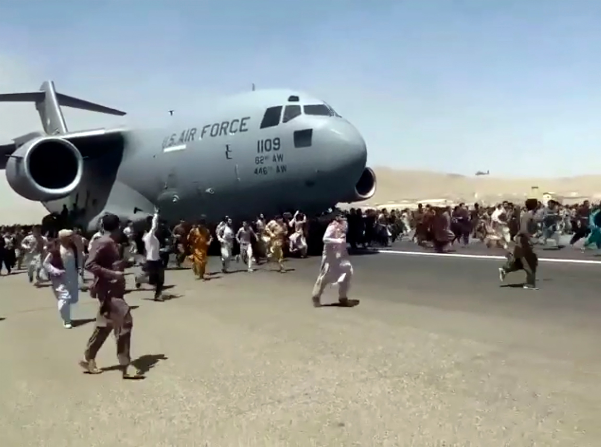 Centinaia di persone corrono al fianco di un aereo da trasporto C-17 della US Air Force mentre si muove lungo l'asfalto dell'aeroporto internazionale, a Kabul, in Afghanistan.