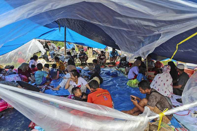 People who are displaced by an earthquake sit under in a makeshift tent at a temporary shelter in Mamuju, West Sulawesi.