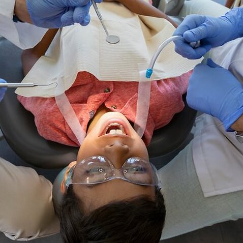 Dentist and dental hygienist checking teeth of boy in dentist office