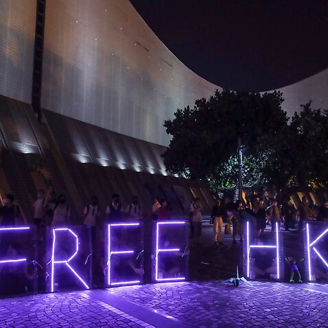 A violet purple 'Free HK' neon sign shines as anti-government protesters take part in a human chain in Hong Kong, China.