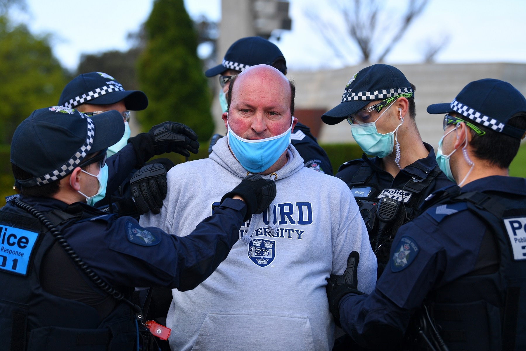 Victoria Police arrest and put a face mask on a protester outside of the Shrine of Remembrance in Melbourne.