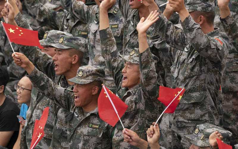 Chinese PLA soldiers hold national flags.  The head of parliament's intelligence committee has warned Australia is facing an increased Chinese threat.
