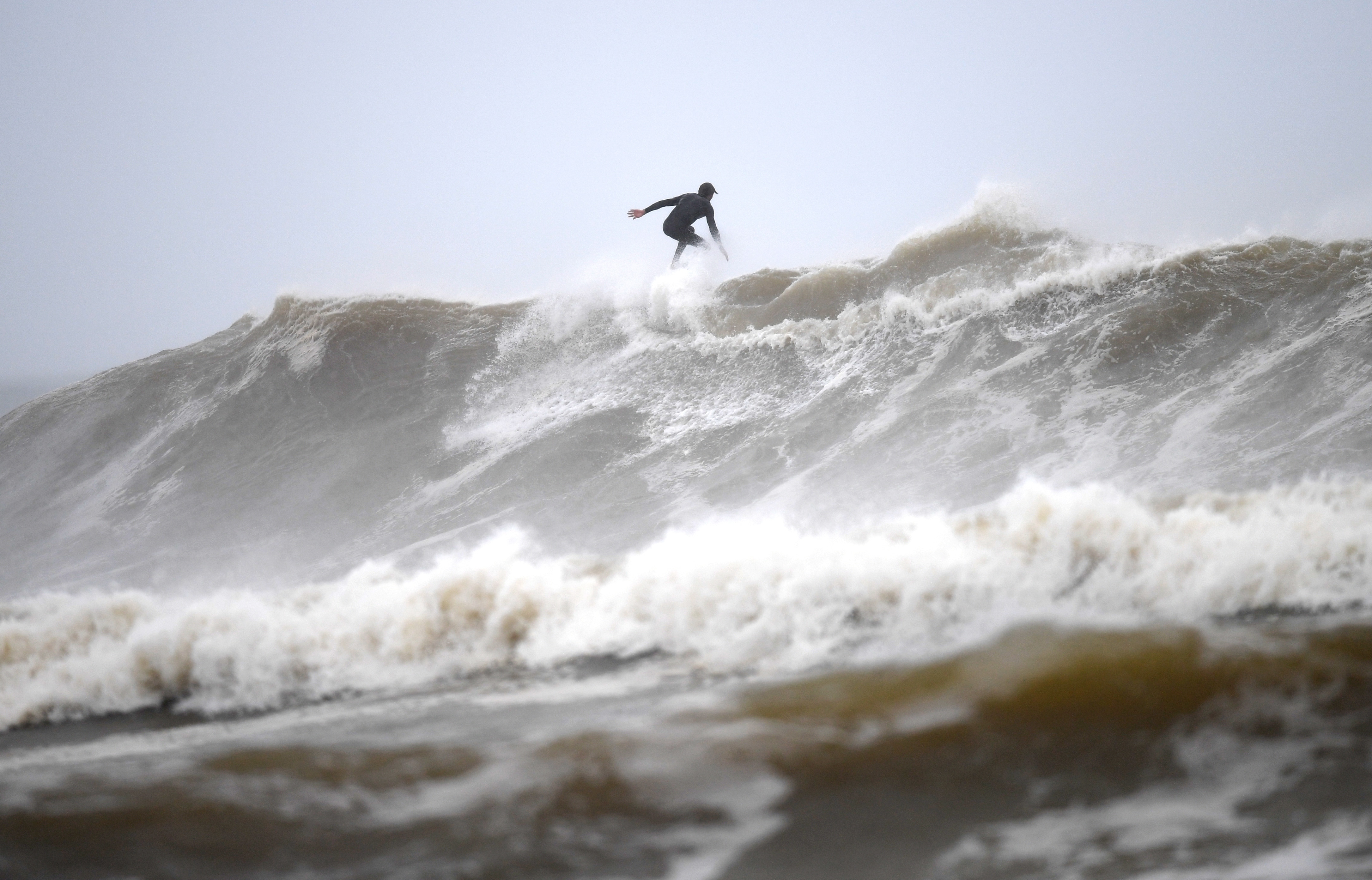 A surfer hits the beach amid wild conditions at Snapper Rocks on the Gold Coast, Sunday, 13 December.