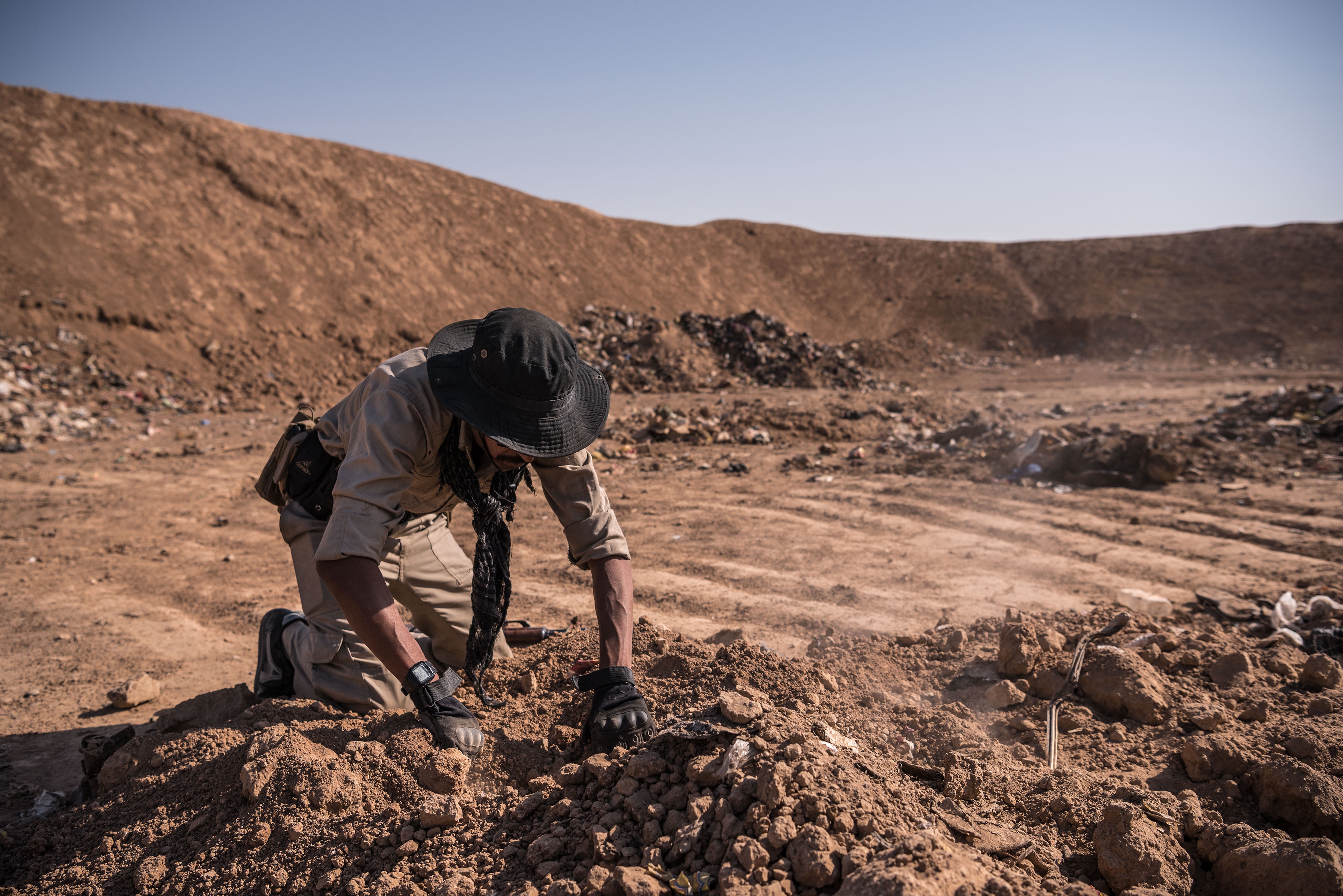 An Iraqi army soldier searches for remains at the mass grave that was discovered at a trash dump site on the outskirts of Hammam Al-Alil after it was liberated by Iraqi forces, in Iraq.