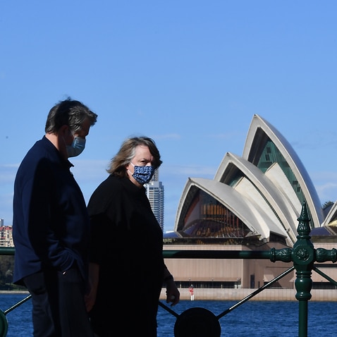 Members of the public, wearing masks, walk past the Sydney Opera House in Sydney.