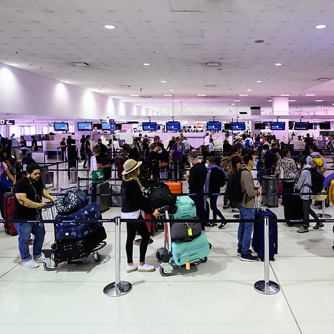 Travellers adhere to social distancing rules as they check in for their flights at the Sydney International Airport, Sydney, Friday, March 27, 2020. 