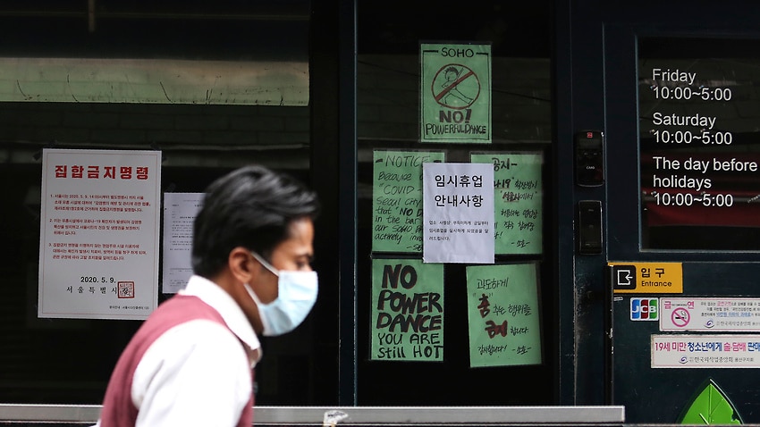 A man waring a face mask passes by notices at the entrance of a temporary closed dance club in Seoul, South Korea, Sunday, May 10, 2020