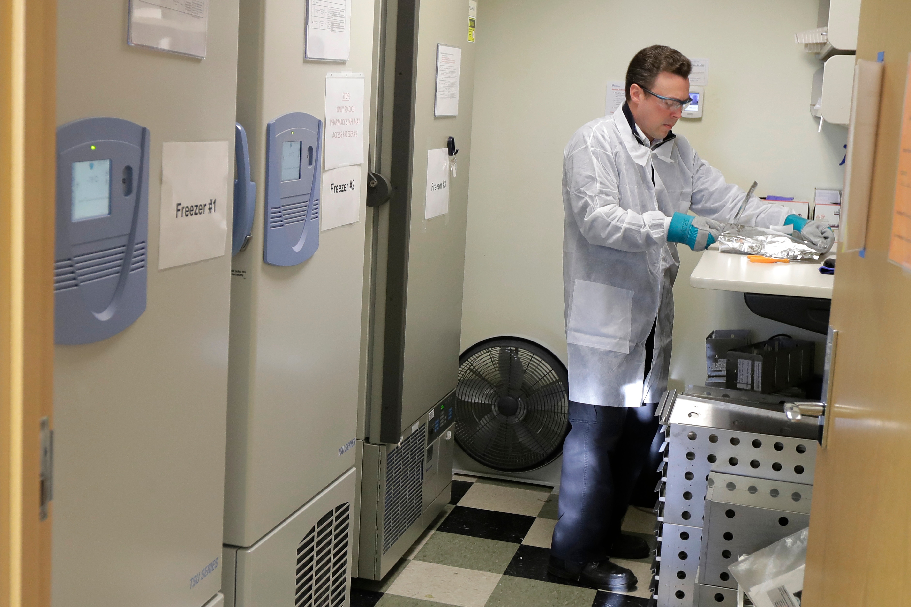 Pharmacist Michael Witte opens a package of the potential vaccine for the COVID-19 coronavirus.