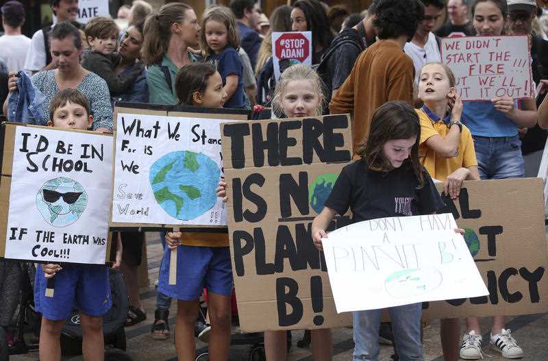 School kids hold handmade signs at a student organised protest outside Tony Abbott's office.