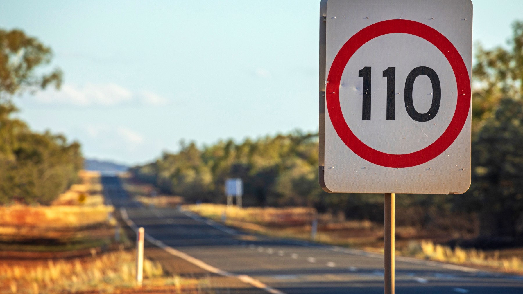 Speed limit road sign 110 kilometres per hour, empty highway in outback Australia