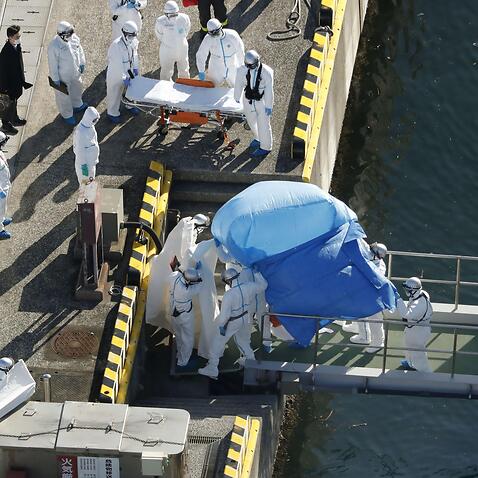Health officials in protective gear transfer infected Diamond Princess passengers to ambulances.