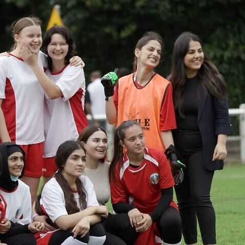 شماری از زنان و دختران تازه‌وارد افغان به همراه دختران محل در یک میدان فوتبال در ساحل شمالی سیدنی.