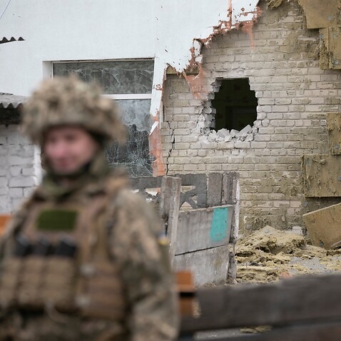 A Ukrainian soldier stands next to a damaged wall after the reported shelling of a kindergarten in the settlement of Stanytsia Luhanska, Ukraine, 