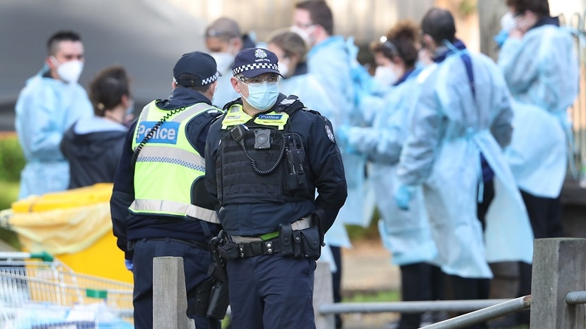 Medical workers and police are seen at a Government Commission tower in North Melbourne on Saturday.
