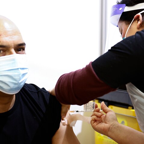 A health worker (right) administers a Pfizer vaccination to a person at a mass coronavirus vaccination hub at the Showgrounds in Melbourne, Monday, July 19, 2021.  (AAP Image/Daniel Pockett) NO ARCHIVING