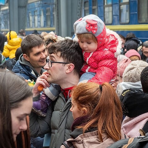 A refugee child seen sitting on her father's shoulder as they try to find a way to leave war torn Ukraine