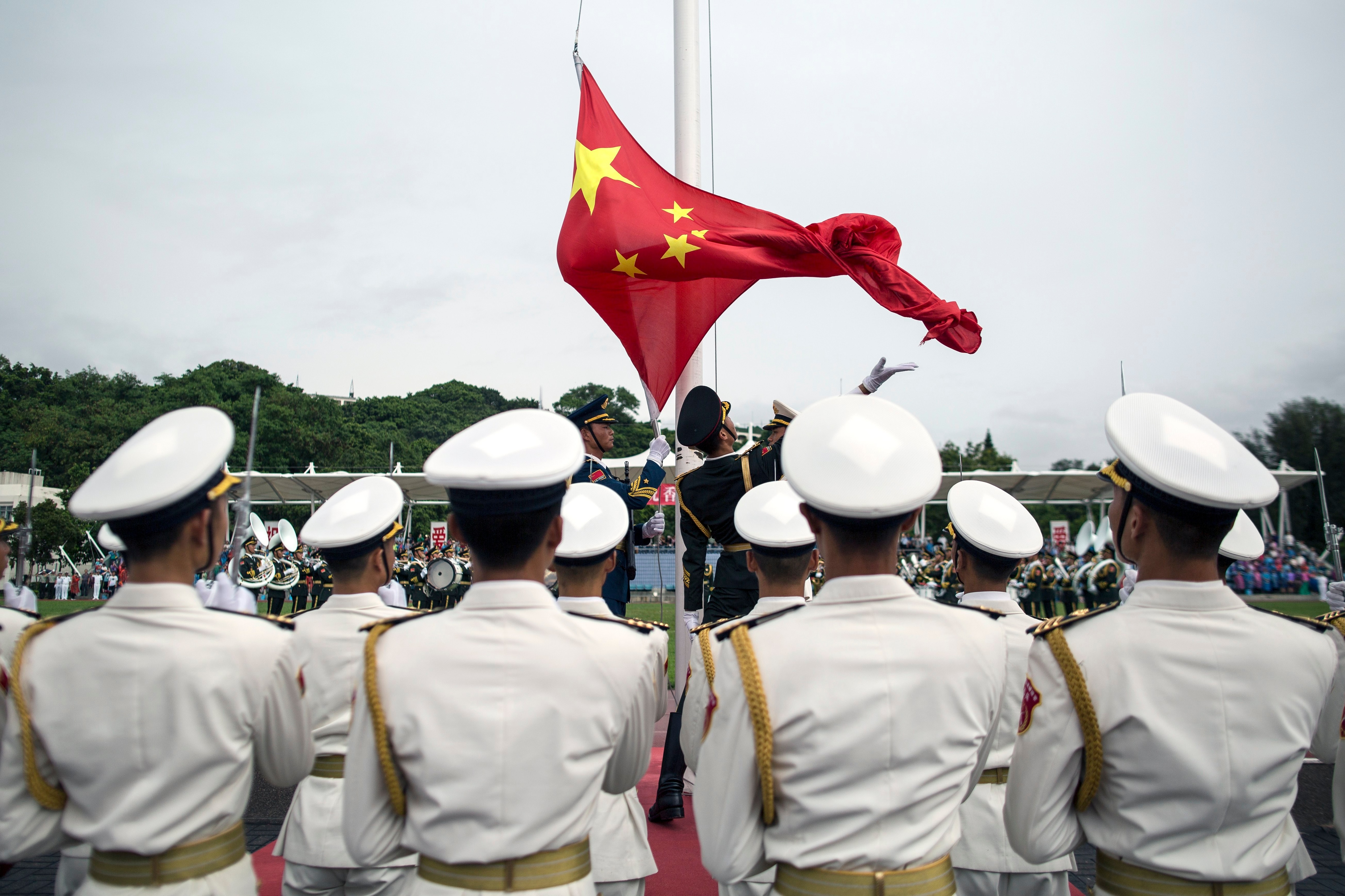People's Liberation Army (PLA) soldiers participate in a flag raising ceremony during an open day at the PLA navy base in Hong Kong.