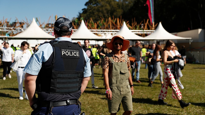 Police officers and drug detection dogs walk amongst festival goers by an entrance to Splendour In The Grass 2019.