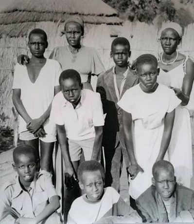 Yuot (bottom left) and his mother (top, second form left) at Pinyudu refugee camp.  