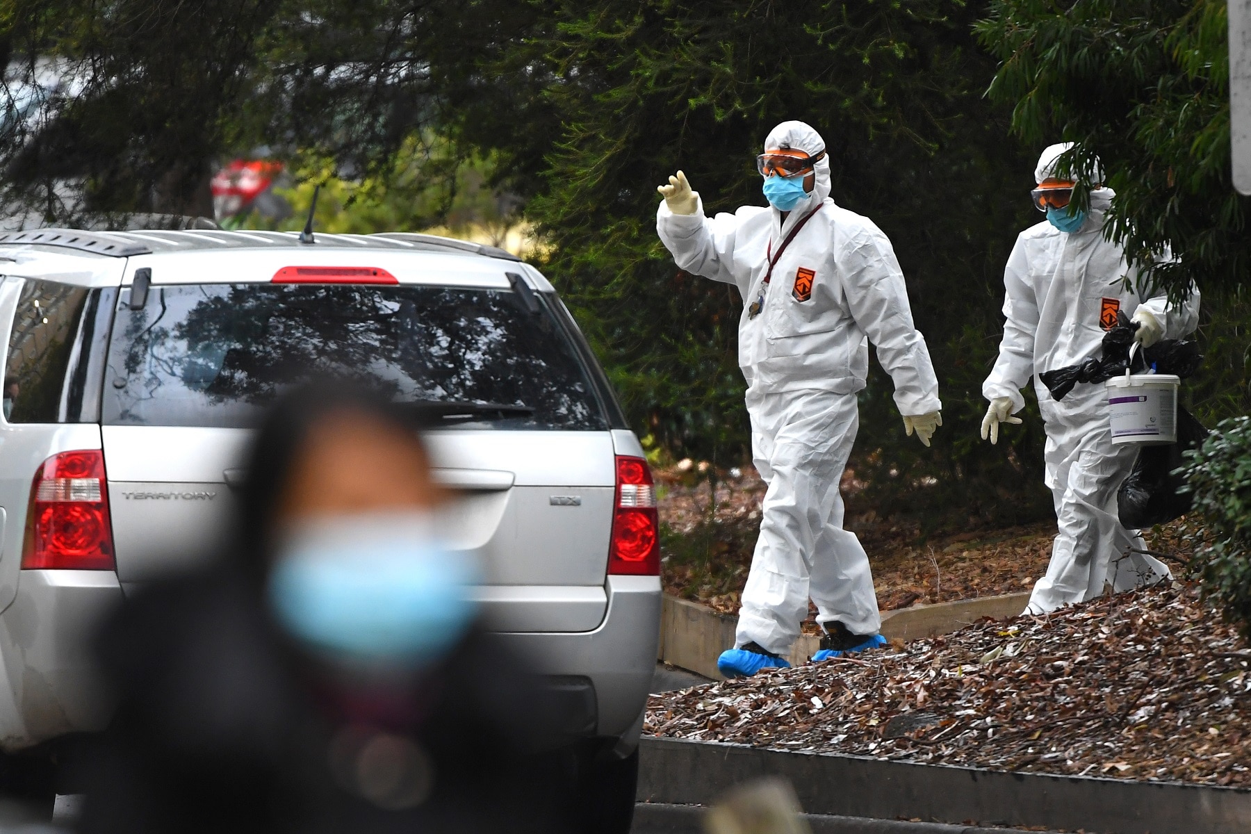 Workers in hazardous material overalls are seen outside of a public housing tower along Racecourse Road in Melbourne. Workers in hazardous material overalls are seen outside of a public housing tower along Racecourse Road in Melbourne.