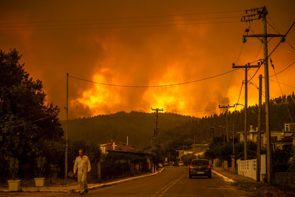 A local resident walks as a wildfire rages near the village of Gouves, on Euboea island, second largest Greek island, on 8 August, 2021. 